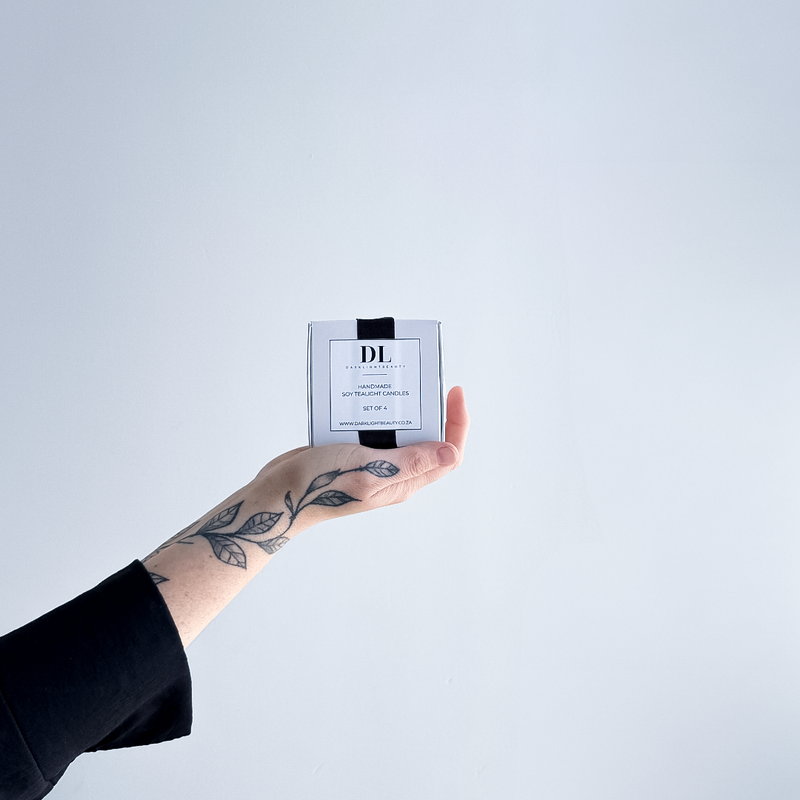 Hand holding soy tea lights box product with a white label against a light gray background