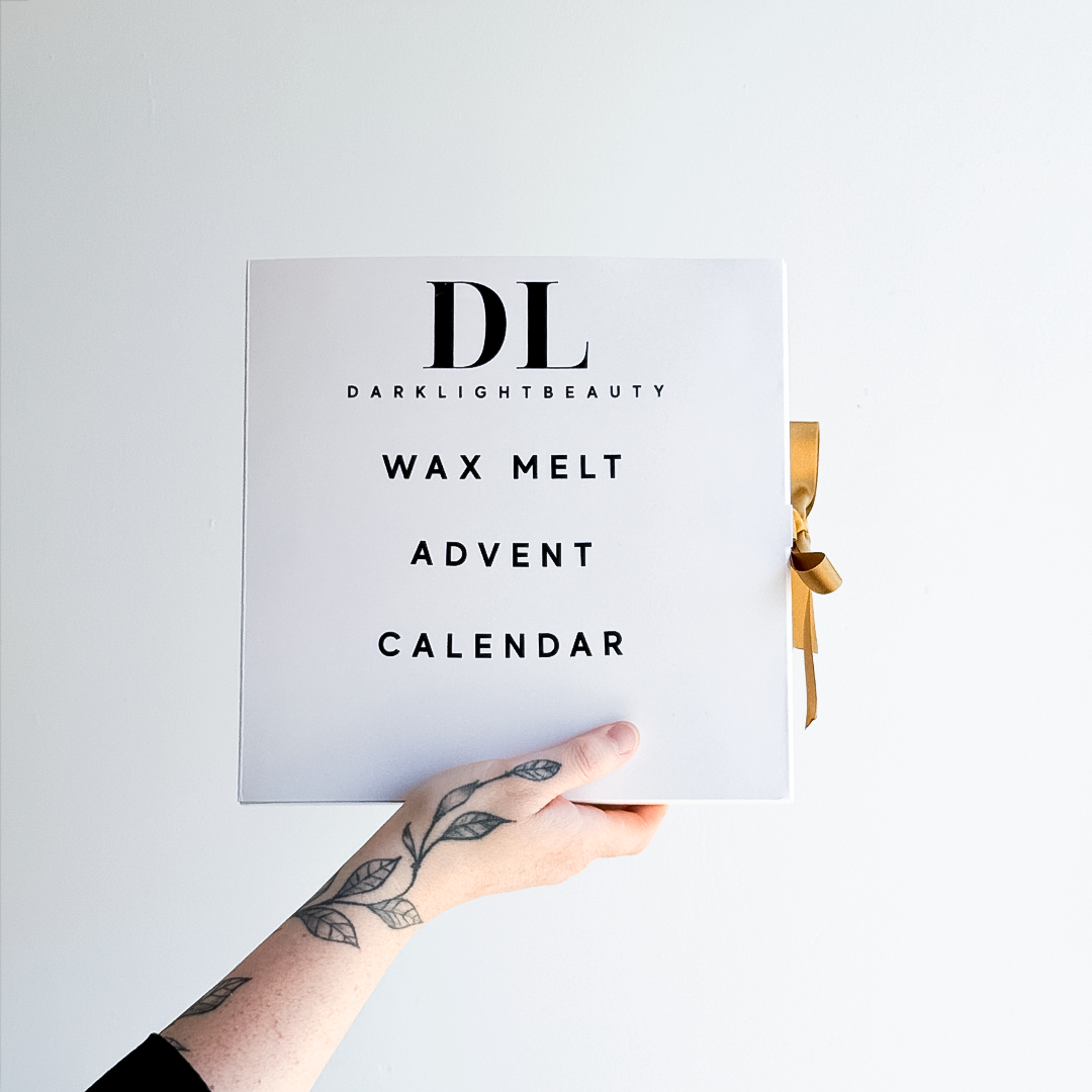 Hand holding a wax melt advent calendar with 'Darklight Beauty' branding on a light gray background.