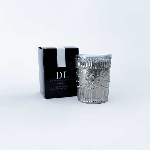 Silver candle holder with decorative design next to a black box with 'DL' branding on a white background