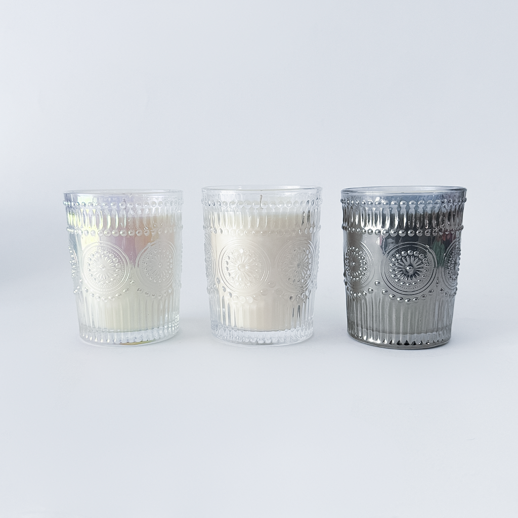 Three glass candle holders with decorative patterns on a white background