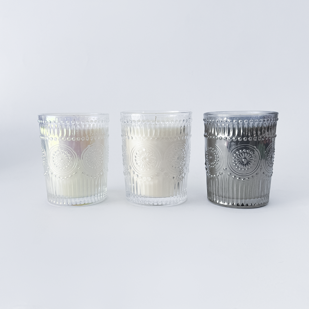 Three glass candle holders with decorative patterns on a white background