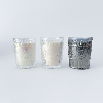 Three glass candle holders with decorative patterns on a white background