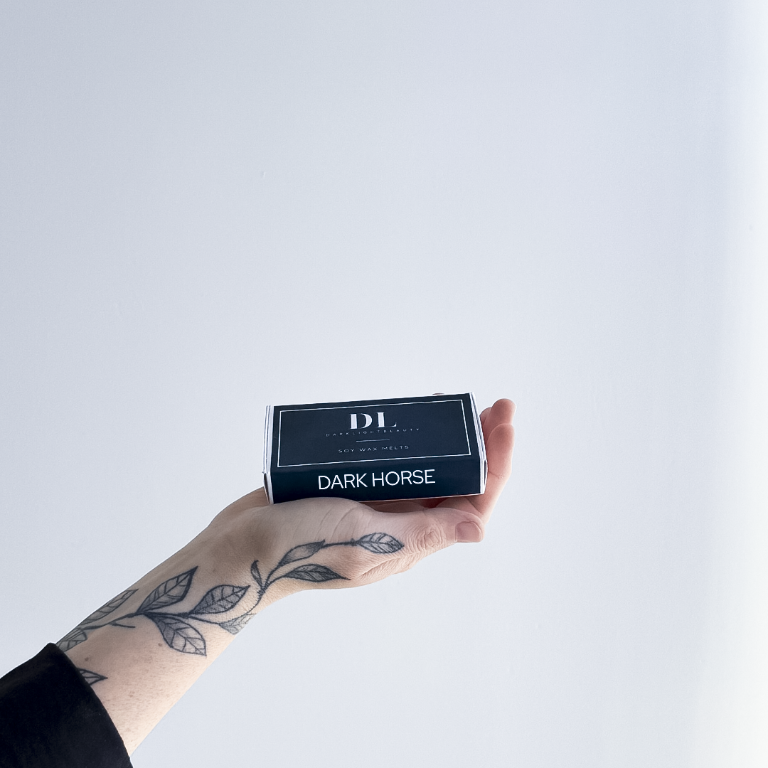 Hand holding a box labeled 'Dark Horse' with 'DL' branding on a light gray background