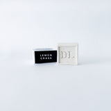 soap abeled 'Lemon Grass' next to a white box with 'DL' branding on a light gray background