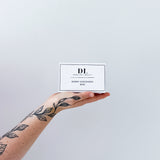 Hand holding a 'DL' scent discovery box against a light gray background