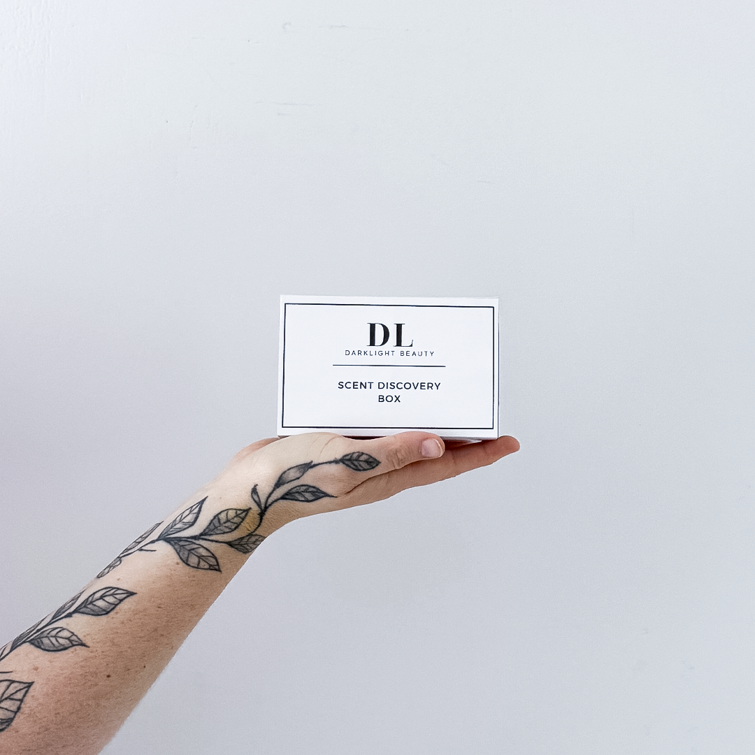Hand holding a 'DL' scent discovery box against a light gray background