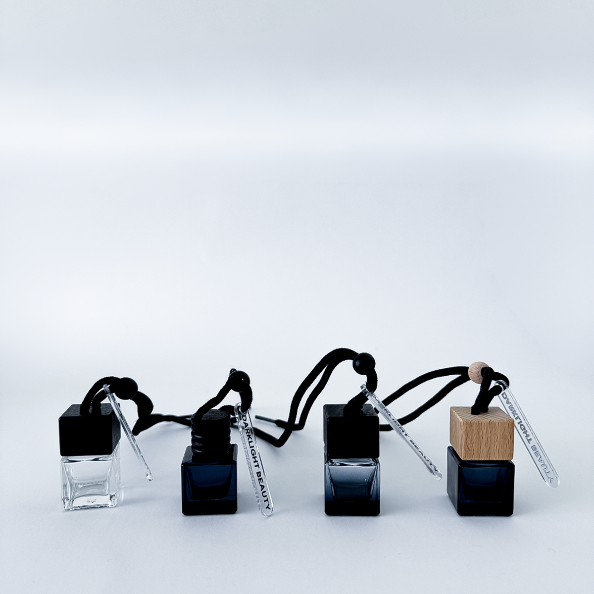 Set of four car diffuser bottles with wooden caps on a light gray background