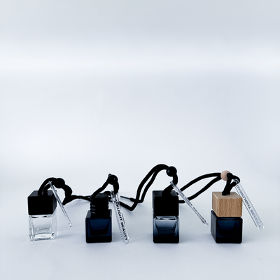 Set of four car diffuser bottles with wooden caps on a light gray background