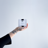 Hand holding soy tea lights box product with a white label against a light gray background