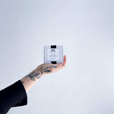 Hand holding soy tea lights box product with a white label against a light gray background