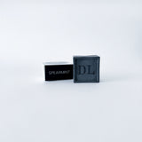 Black soap bar with 'DL' branding and a black container labeled 'Spearmint' on a white background