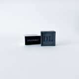 Black soap bar with 'DL' branding and a black container labeled 'Spearmint' on a white background
