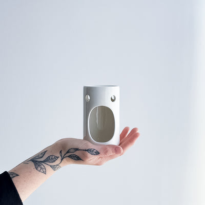 hand holding a gloss white ceramic oil burner 