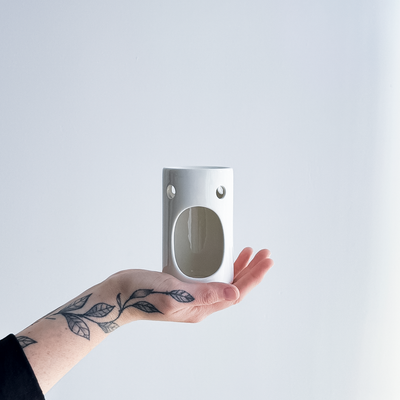 hand holding a gloss white ceramic oil burner 