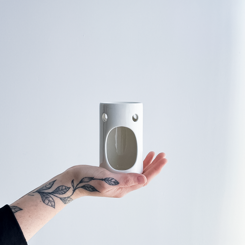 hand holding a gloss white ceramic oil burner 